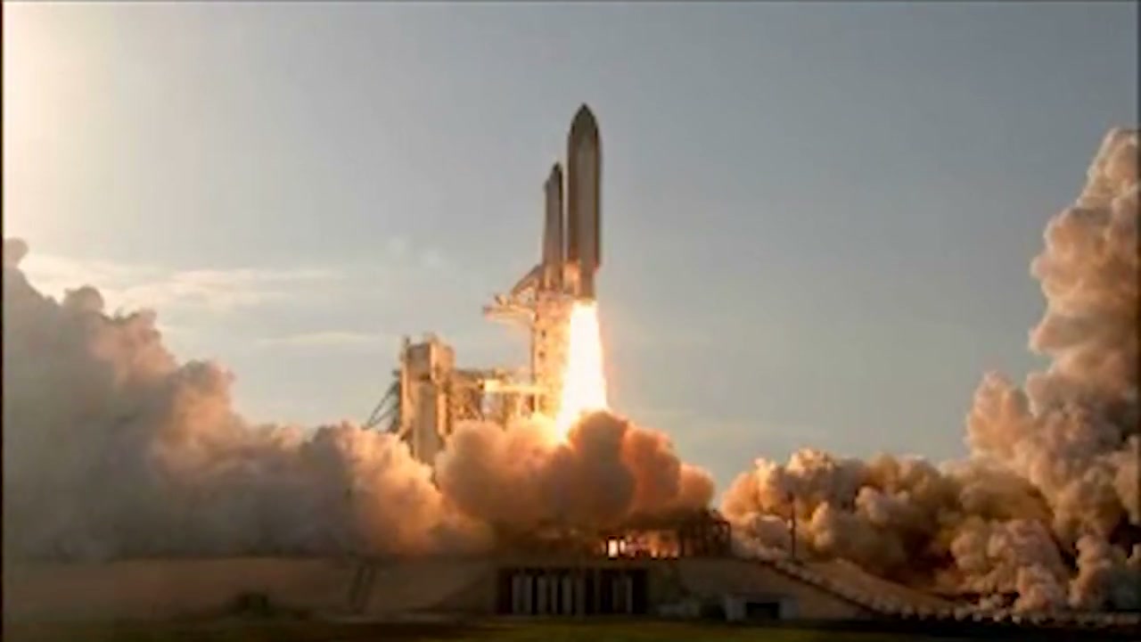 Space Shuttle Discovery lifting off on a plume of fire during STS-133